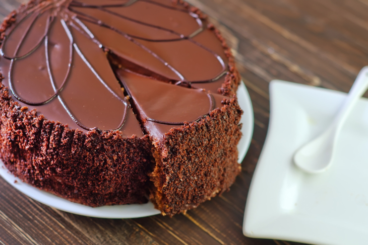 En rund chokladtårta med chokladfrosting ringlat ovanpå.  
