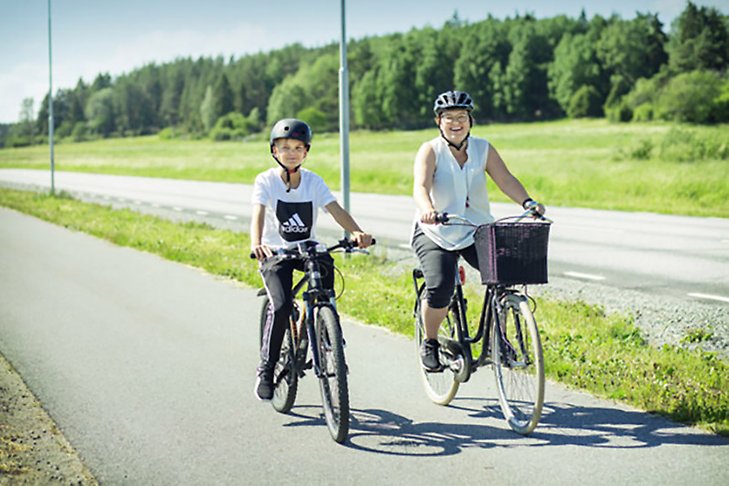 Mor och son på cykelfärd längs landsväg i kommunen.