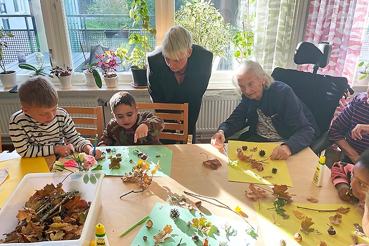 barn och äldre runt ett bord med kottar, löv och ekollon.
