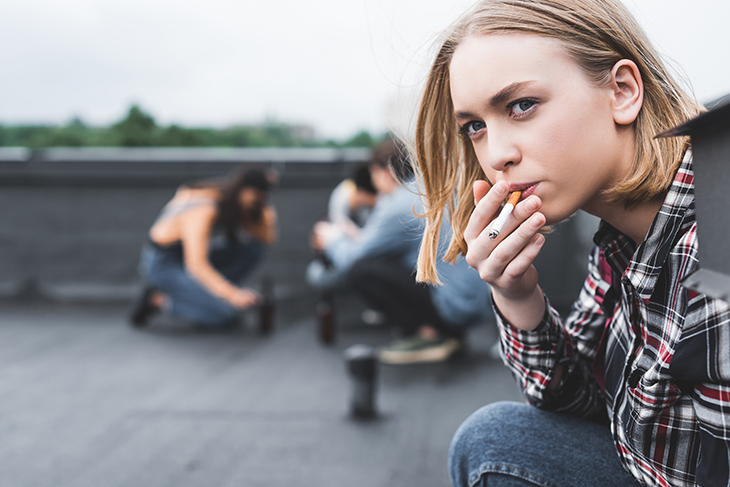 En ungdom som sitter och röker en cigarett 
