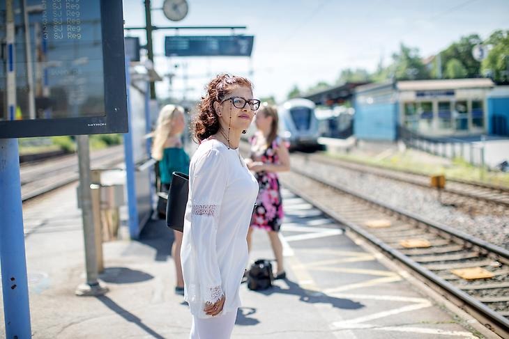 En kvinna står och väntar på tåget vid Märsta station.