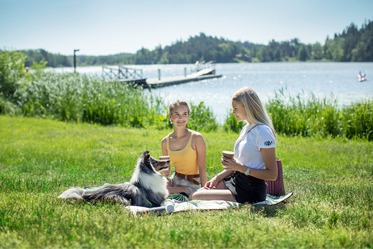 Två flickor och en hund har picknick i Rosersbergsviken. Fotograf: Rosie Alm (sam16, sam17)