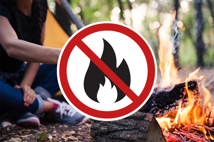 Symbol med överstruken eldsvåda på en bild där en kvinna sitter vid en grillplats i naturen.