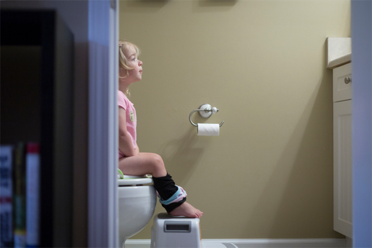 En liten flicka som sitter på toaletten