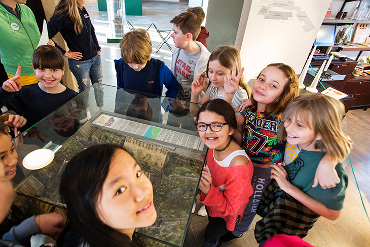 Barn står runtom en glasmonter med en modell av Sigtuna på vikingatiden. 