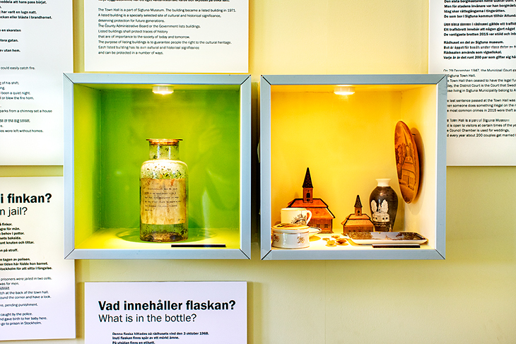 En flaska som står i en utställningsvitrin. I en annan utställningsvitrin står olika små modeller av Sigtuna rådhus. Utställningstexter runtom vitrinerna. 
