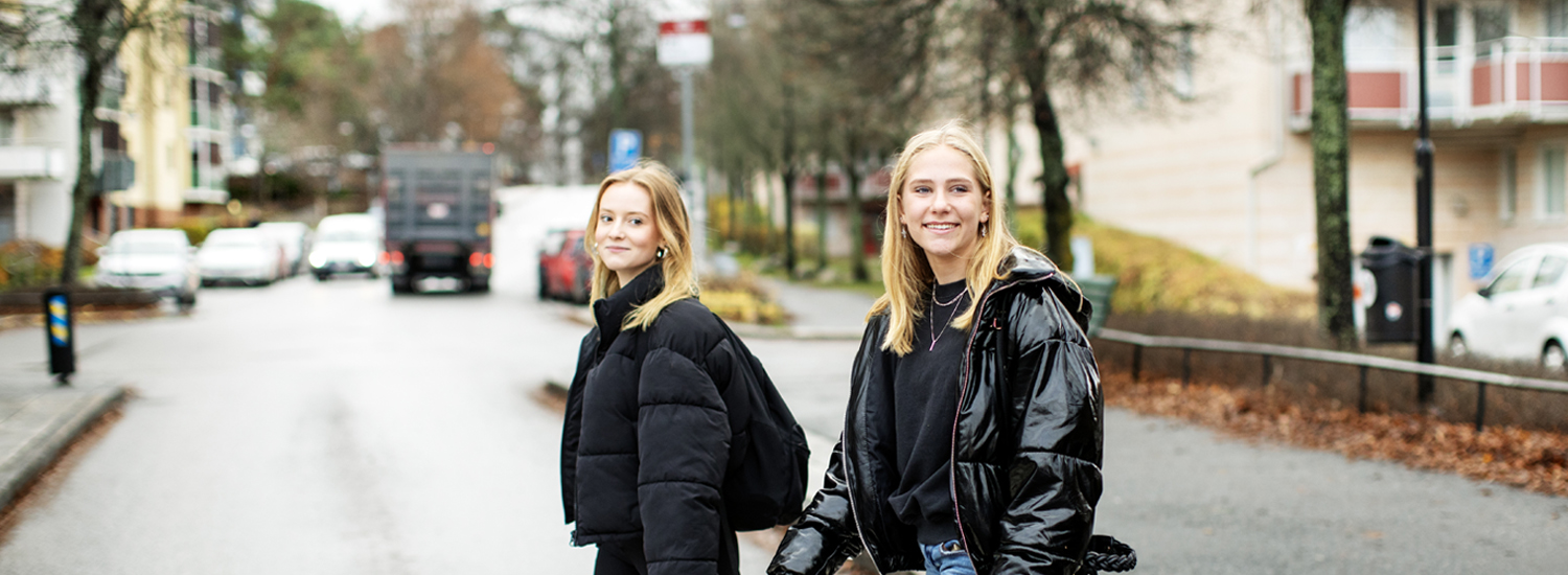 Två unga tjejer går över Södergatan i Märsta intill en busshållsplats. Fotograf: Rosie Alm