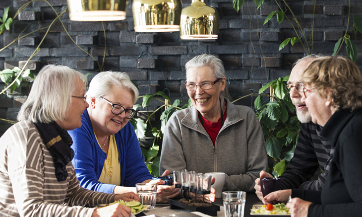 Fyra äldre människor äter och skrattar.