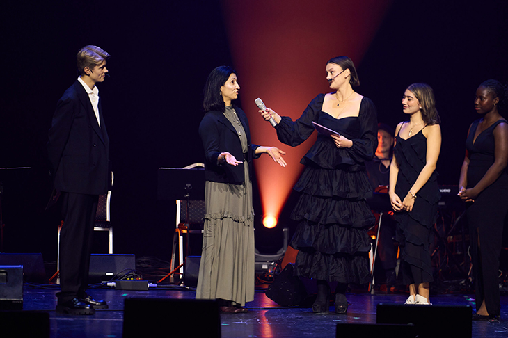 Fem personer står scenen med Zahra i klänning i mitten. 