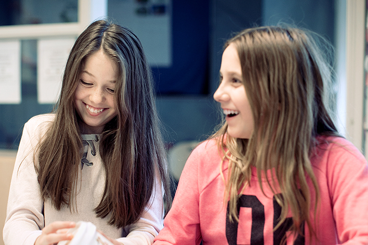 Två elever skrattar under en lektion. Fotograf: Rosie Alm