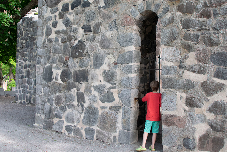 Ett barn kikar in mellan murarna på S:t Olofs kyrkoruin. 