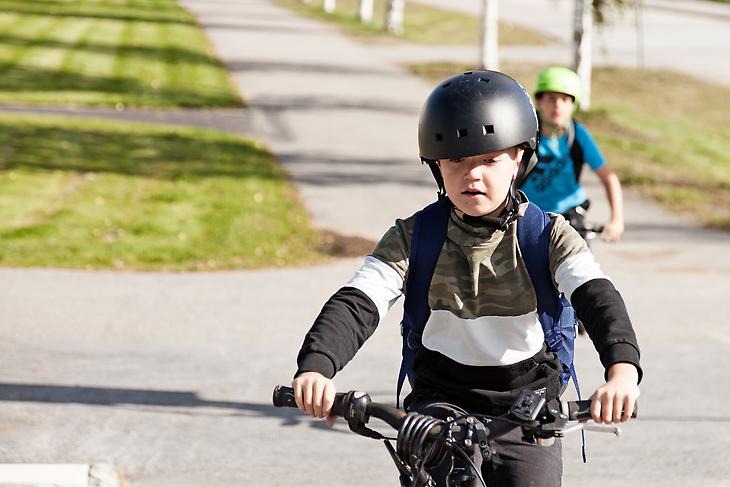 Två barn som cyklar på en gång- och cykelväg.