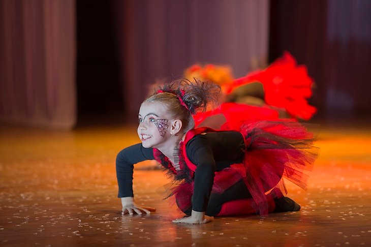 Ung flicka i röda kläder uppträder på en scen.