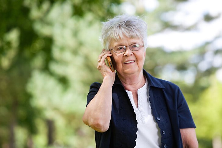 Vanhempi nainen pitää puhelintansa korvaan.