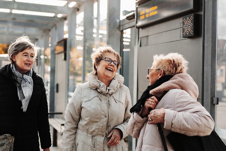 Tre glada äldre kvinnor i vinterkläder.