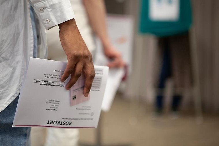 Människor i kö med röstkort i händerna