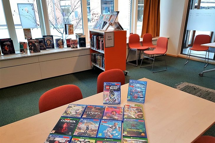 Massor av tv-spel på ett bord i Green Room på Märsta bibliotek.