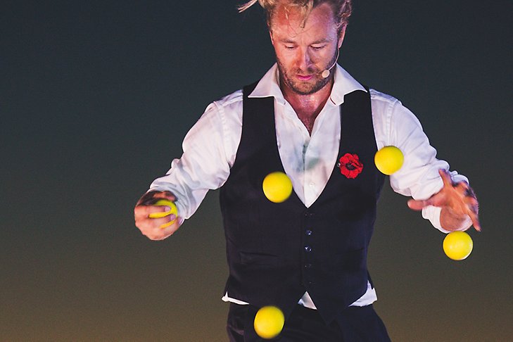 En man jonglerar med gula bollar. 