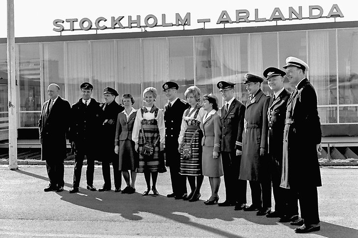 Män och kvinnor poserar på rad framför Stockholm Arlanda flygplatsterminal.