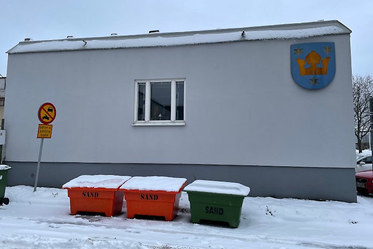 Tre lådor med sand och stenflis utanför kommunens hus för drift och service på Östra bangatan 3