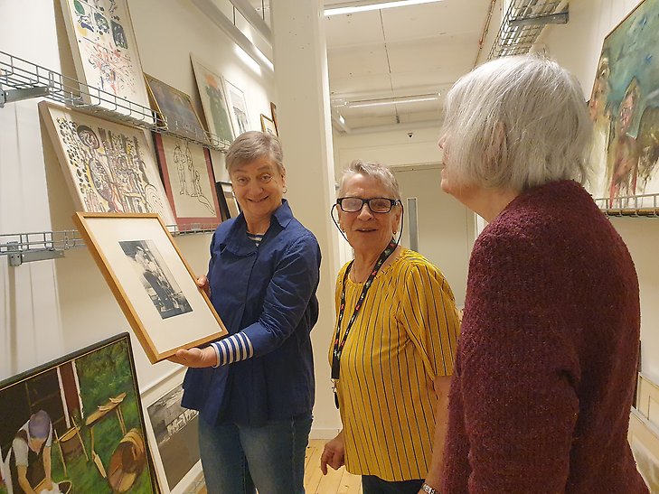 Tre kvinnor tittar på ett konstverk