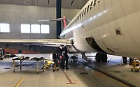 Flygplan i hangar på Arlanda flygplats. Två elever arbetar vid vingen. 