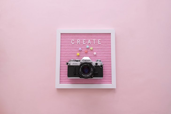 En tavla med en kamera och pärlor och ordet Create.
