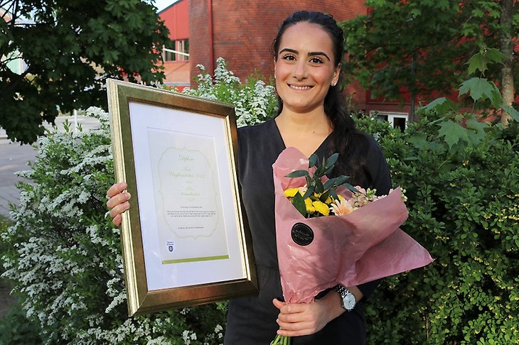 Manuella Azri med diplom och blommor.