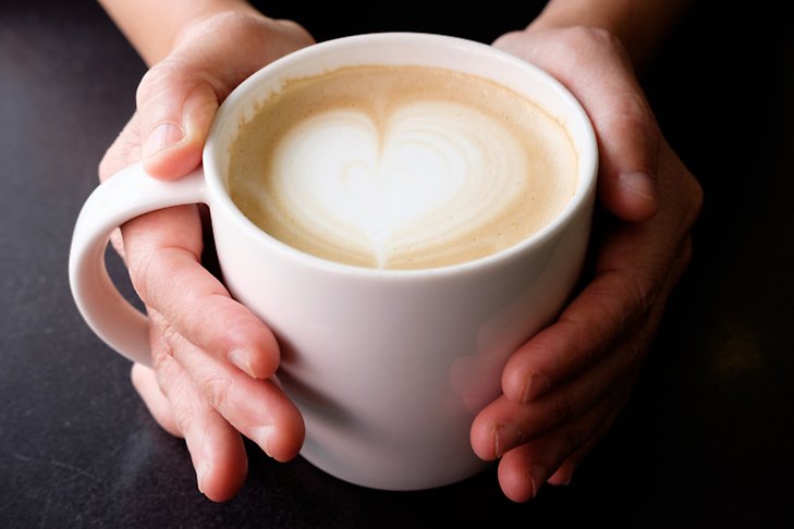 Två händer håller i en varm kaffekopp
