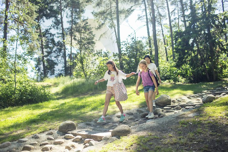 Tre unga tjejer i sommarskogen vid vattentornet i Valsta.
