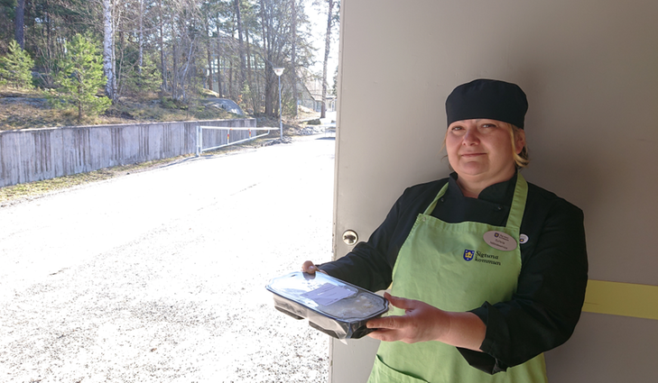 Sylwia Karlsson kökschef på St Olofs skola delar ut matlådor. Fotograf Sigtuna kommun