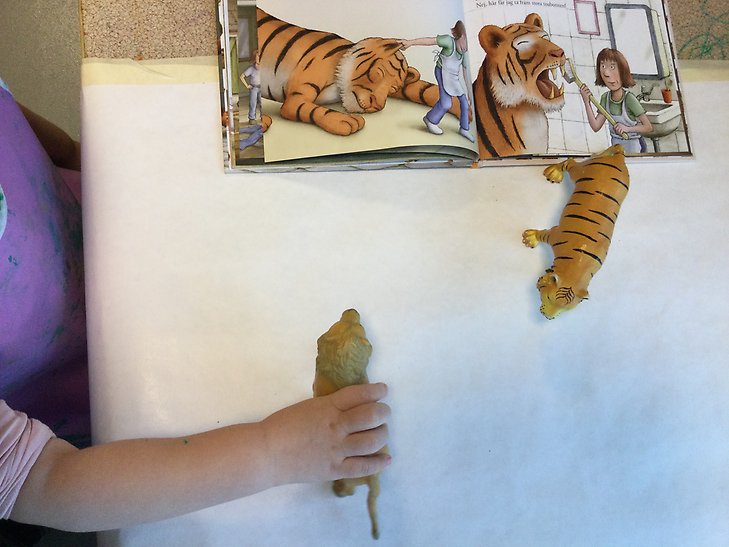Barn leker med leksakstigrar och läser en bok med tigrar i. Foto: Sigtuna kommun