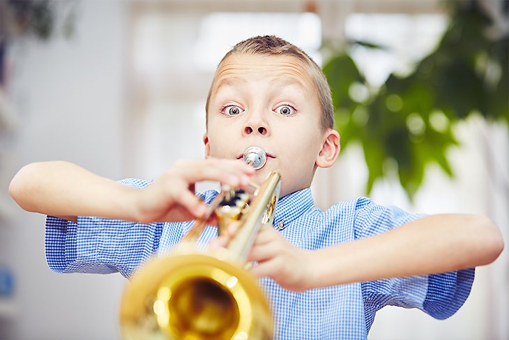 Pojke spelar trumpet.