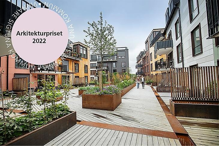 Bild av området Gretas glänta, som är vinnare av arkitekturpriset 2022. Trädäck, blomlådor i cortenplåt och byggnader syns i bilden.