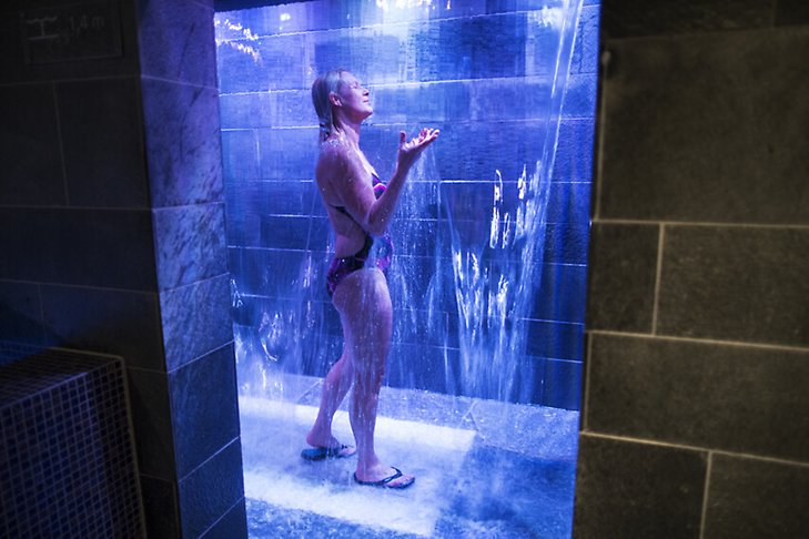 En kvinna duschar i en dusch med blått ljus.