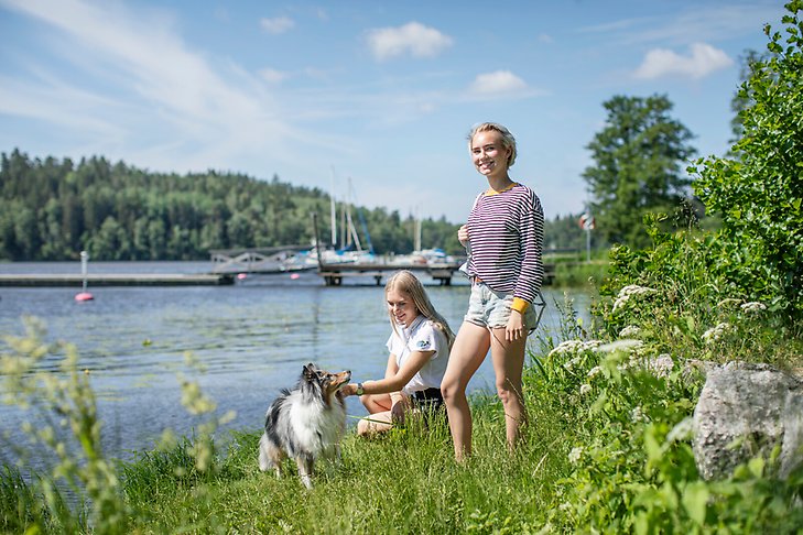 Två tjejer och en hund har picknick vid Rosersbergsviken. Fotograf: Rosie Alm.