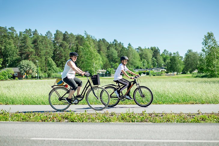 Mamma och son cyklar längs landsvägen.