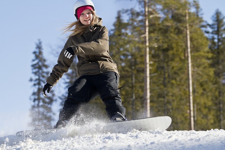 En ung tjej åker snowboard.